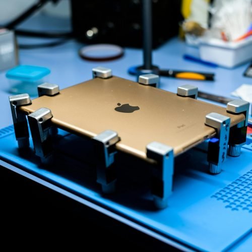 A close-up view of a tablet undergoing repair in a tech workshop with specialized tools.